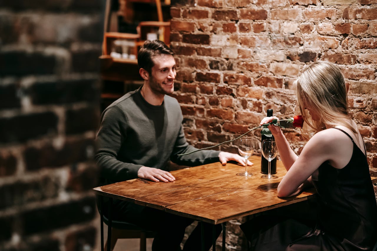 The Art of Drawing Readers In: Your attractive post title goes here Young couple in elegant clothes sitting in light cafeteria at wooden table near brick wall and having romantic dinner with red rose and wine near glasses